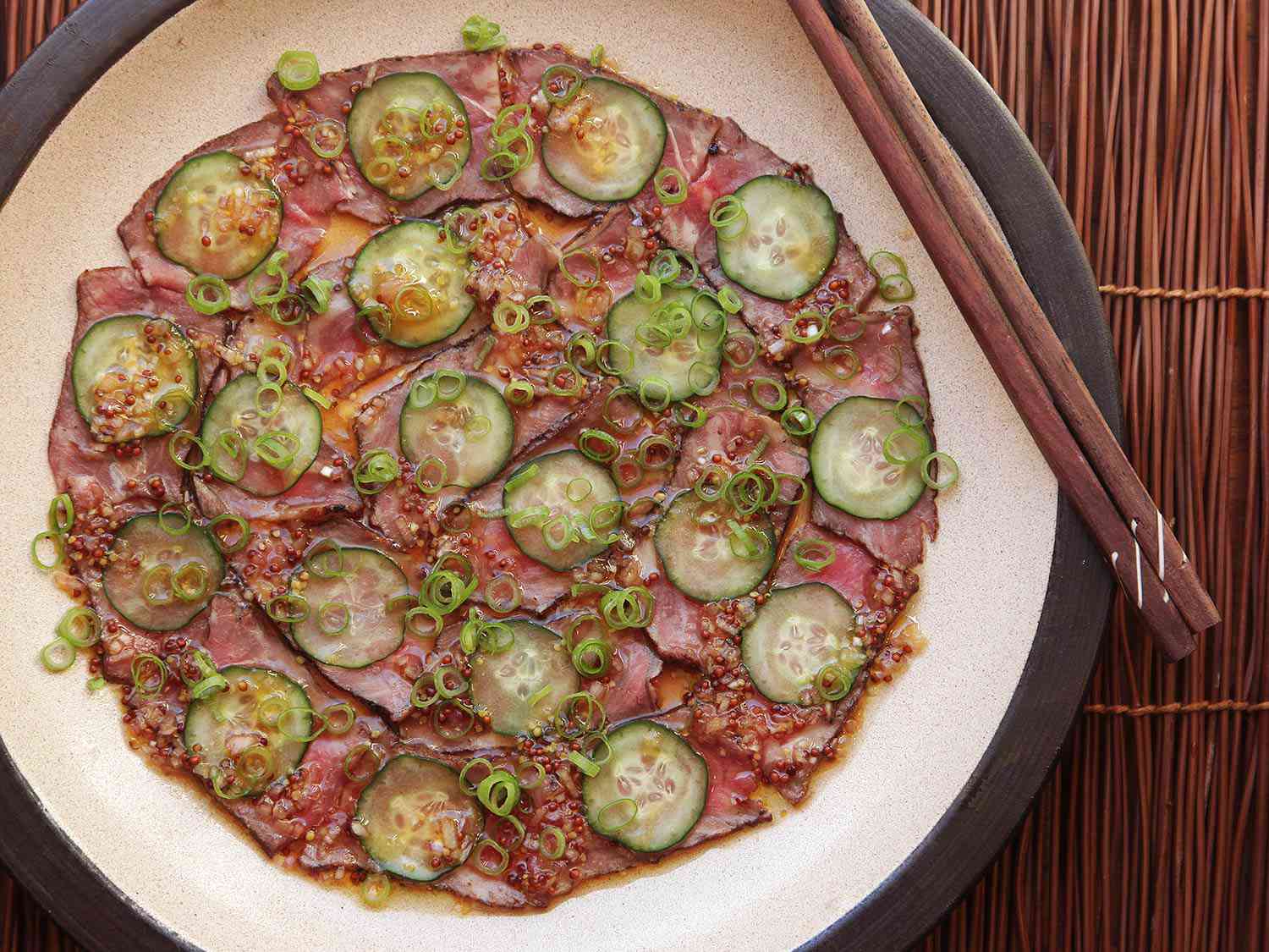 Overhead view of cold steak salad with cucumber served on a large plate.