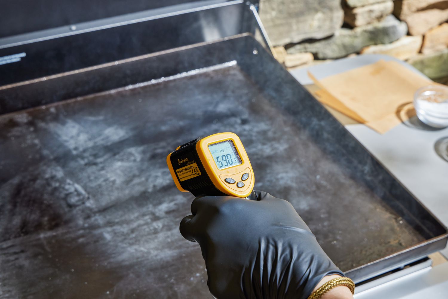 A person measures the temperature on the top of the Weber 36 Inch Gas Griddle