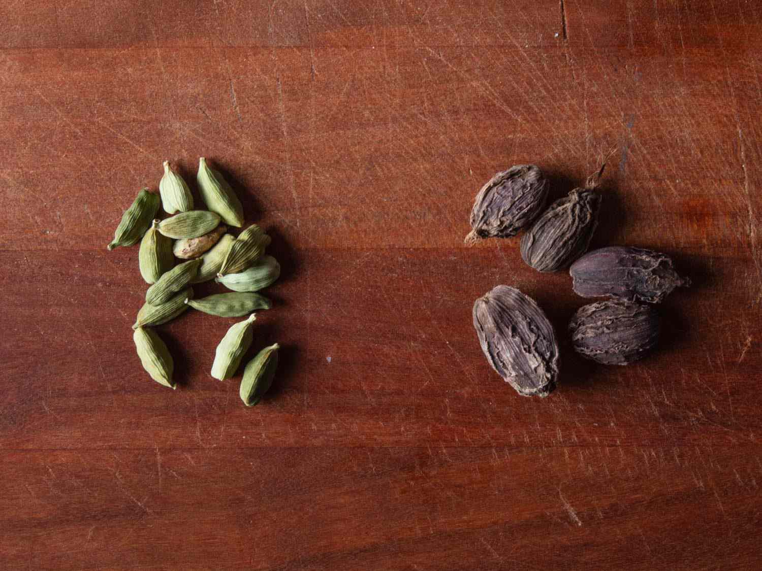 Side by side comparison of green cardamom pods (left) and brown cardamom pods (right)