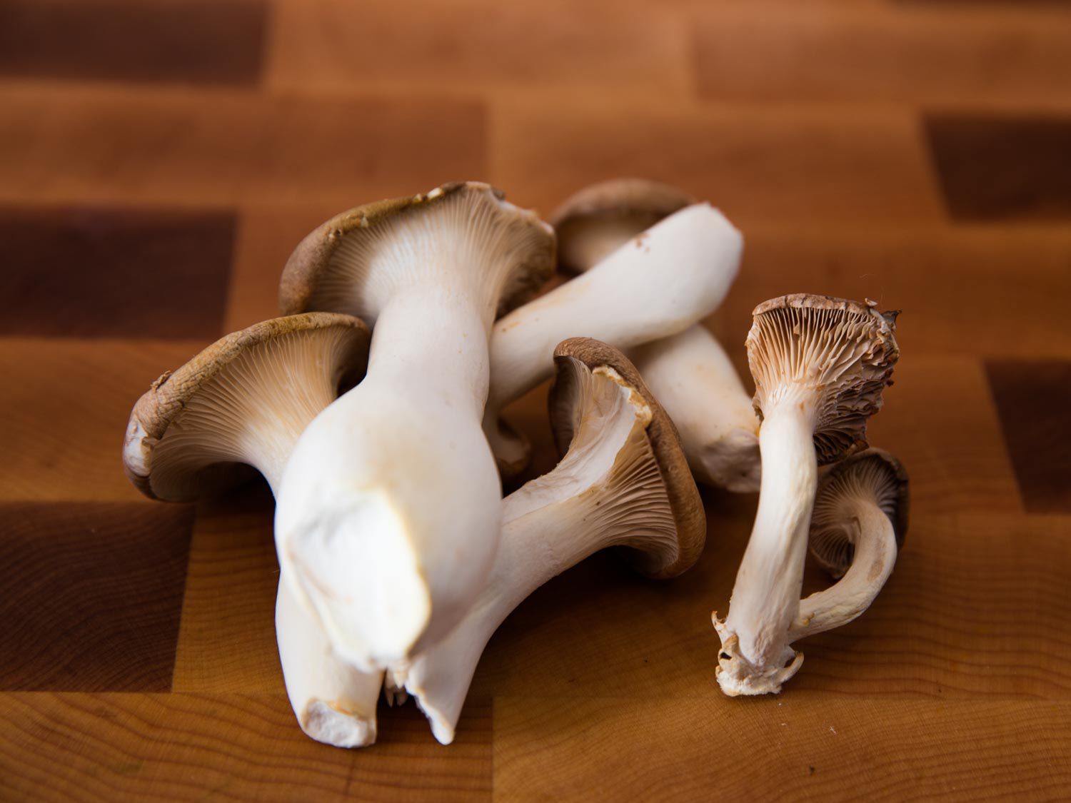 Close-up of king oyster mushrooms on an end-grain cutting board.