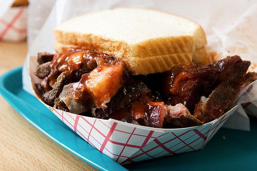 A rib tips sandwich in a red and white cardboard tray. 