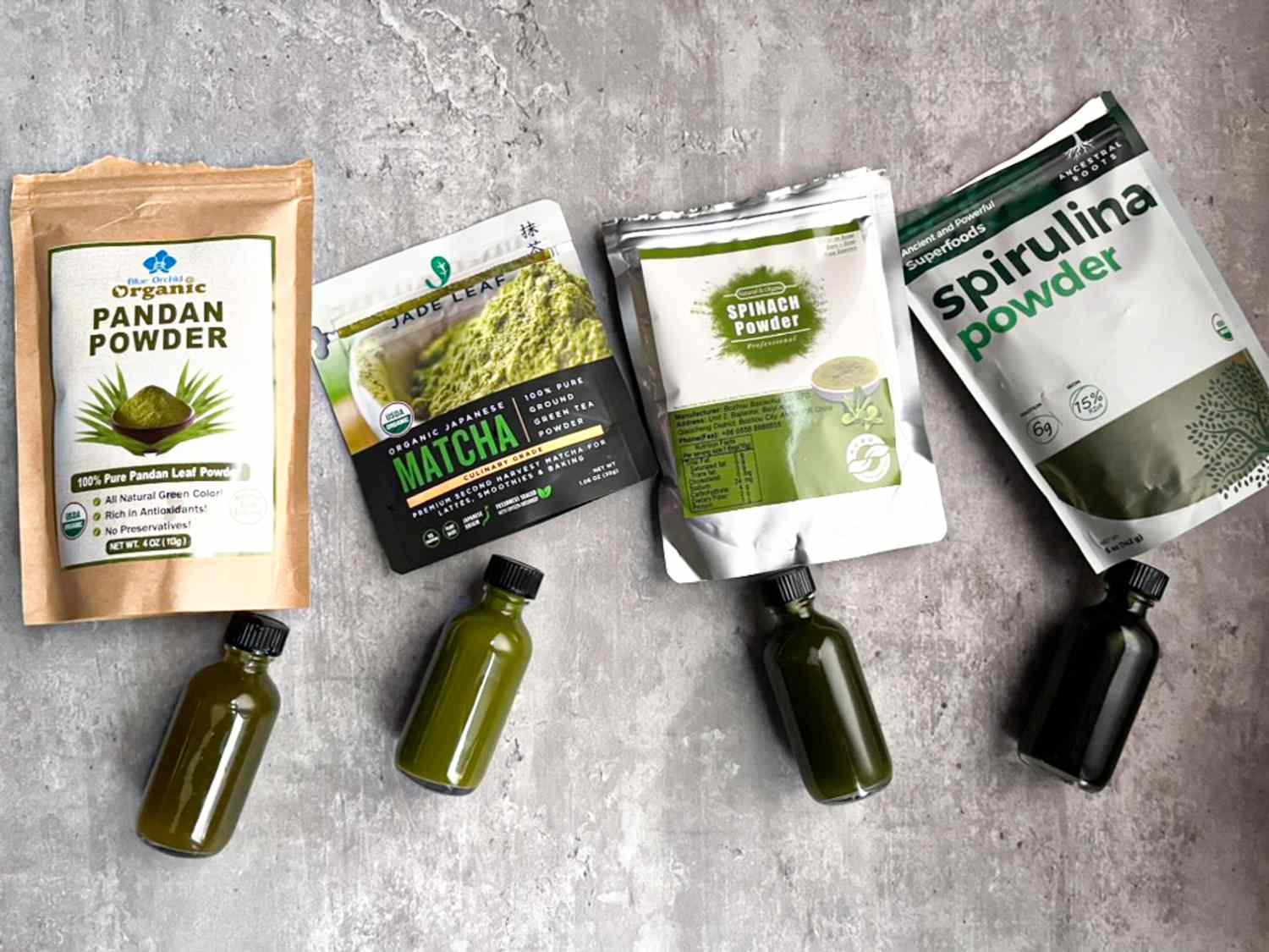 Bags of pandan, matcha, spinach, and spirulina powders with bottles of each