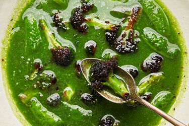 A green soup with broccoli leeks and snap peas served with a spoon