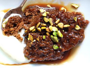 Closeup of a serving of sticky toffee pudding, topped with chopped pistachios.