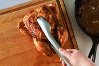Hand using the Material Kitchen The Only Tongs to pick up a whole chicken