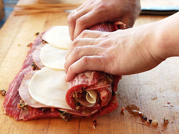 Rolling up a butterflied flank steak stuffed with cold cuts and cheese