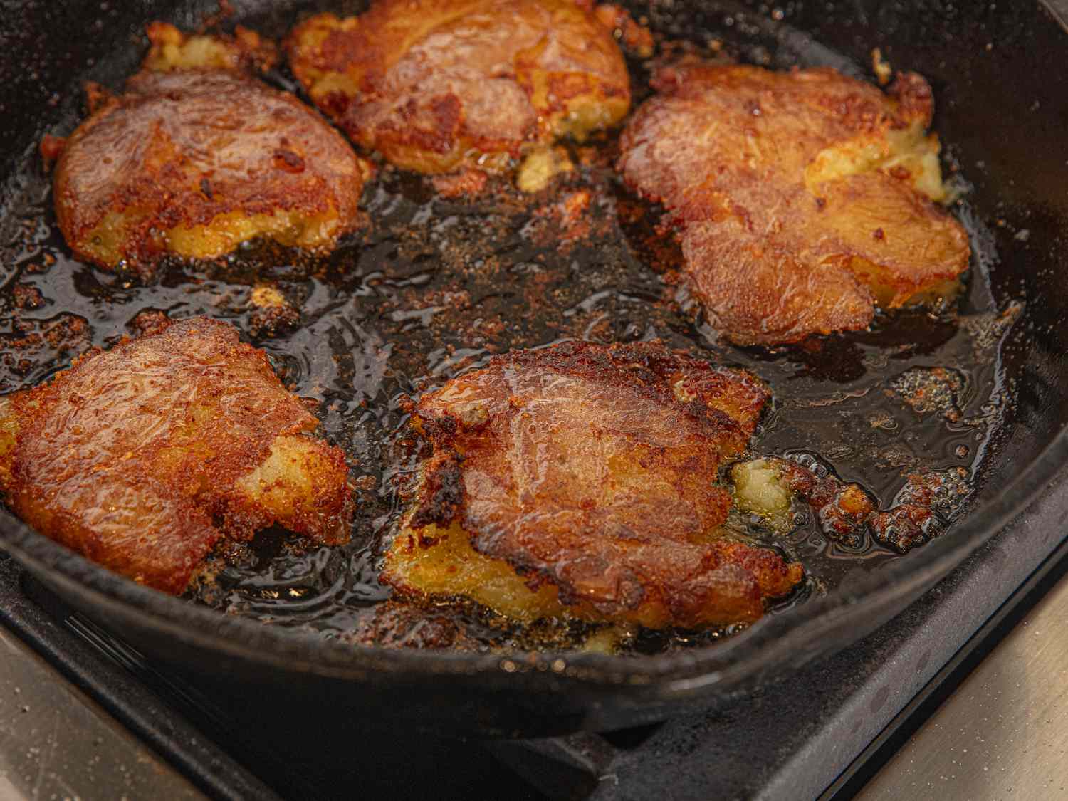 Pan-fried smashed potatoes cooking in a skillet