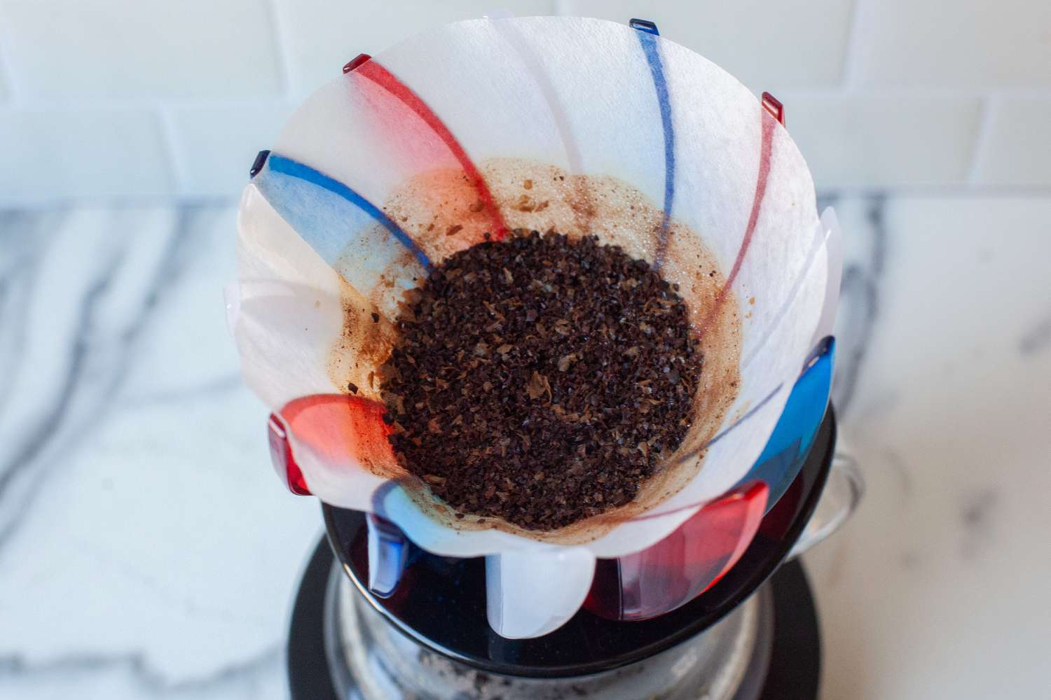 A coffee pour-over filter containing brewed coffee grounds placed on a dripper