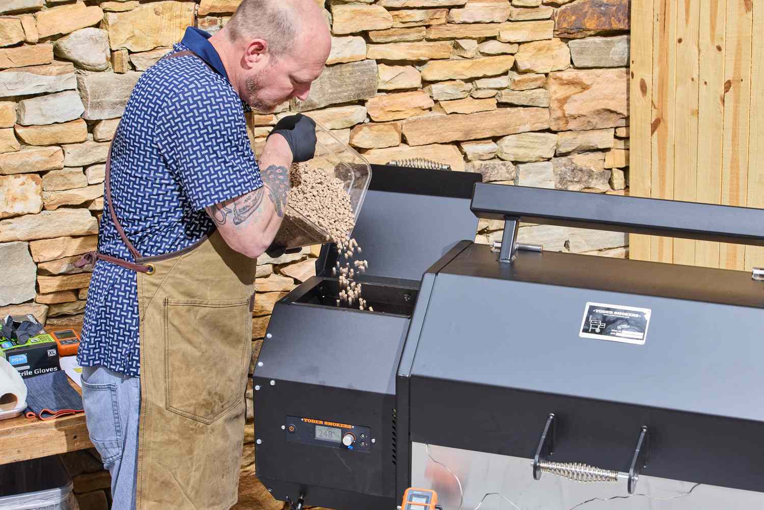 A person pours pellets into the Yoder Smokers YS640S Pellet Grill