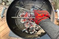 A person holds tongs while wearing the Comsmart BBQ Gloves