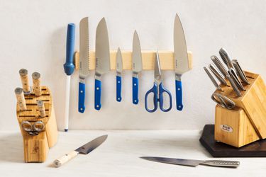 Two knife blocks and one magnetic knife strip set on a marble countertop and white wall.