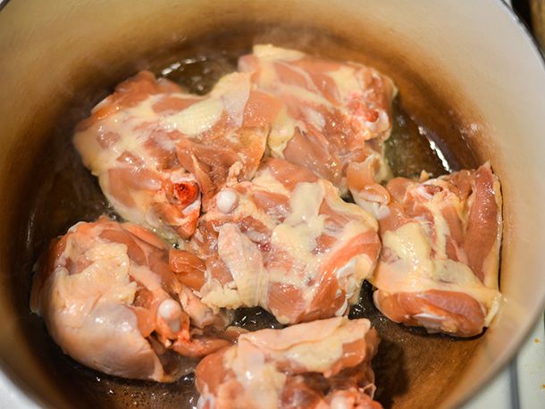 Chicken thighs getting browned in a Dutch oven, skin-side down.