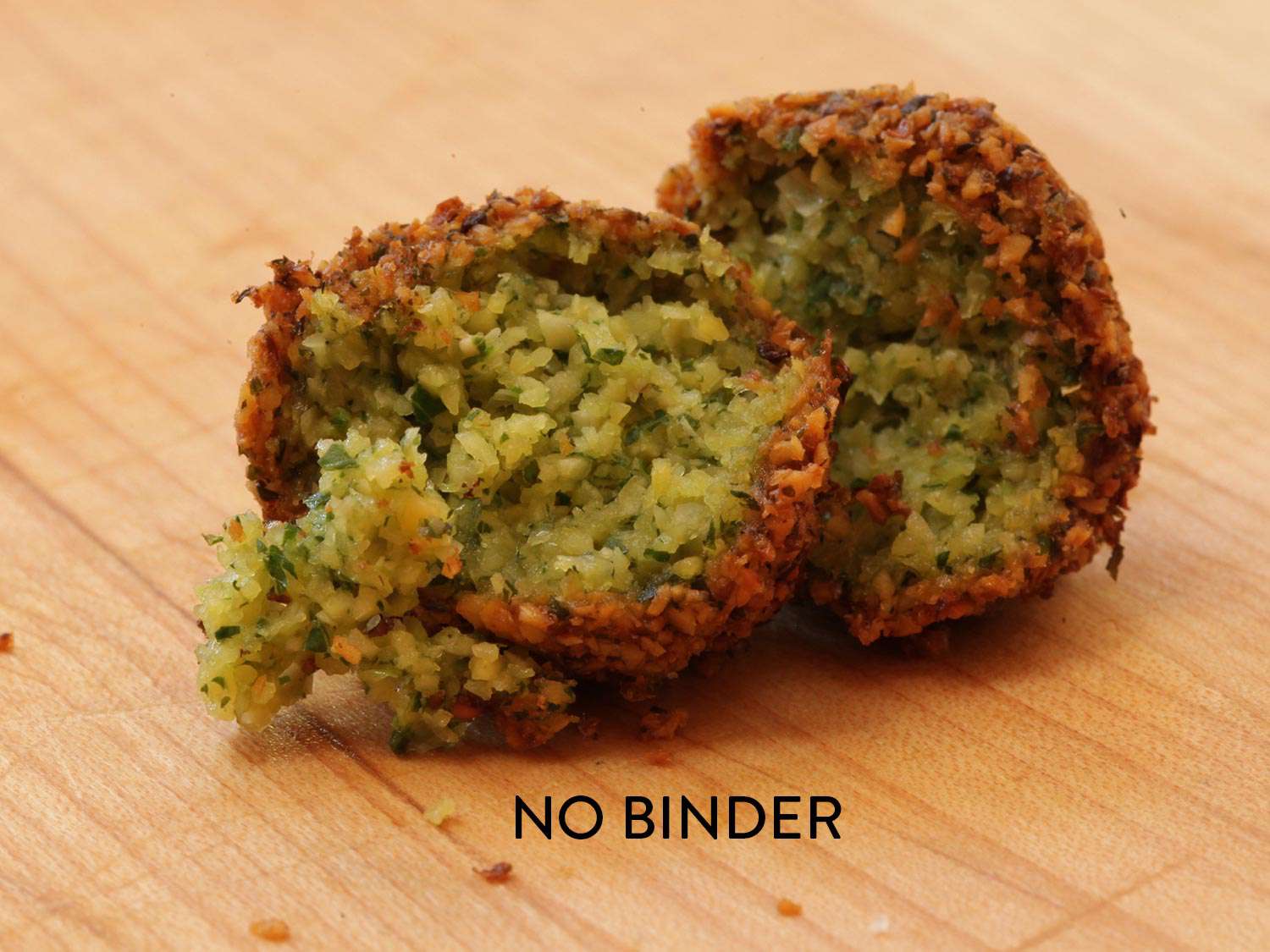 A cooked falafel torn in half, showing the interior. The image is labeled with the words "no binder."
