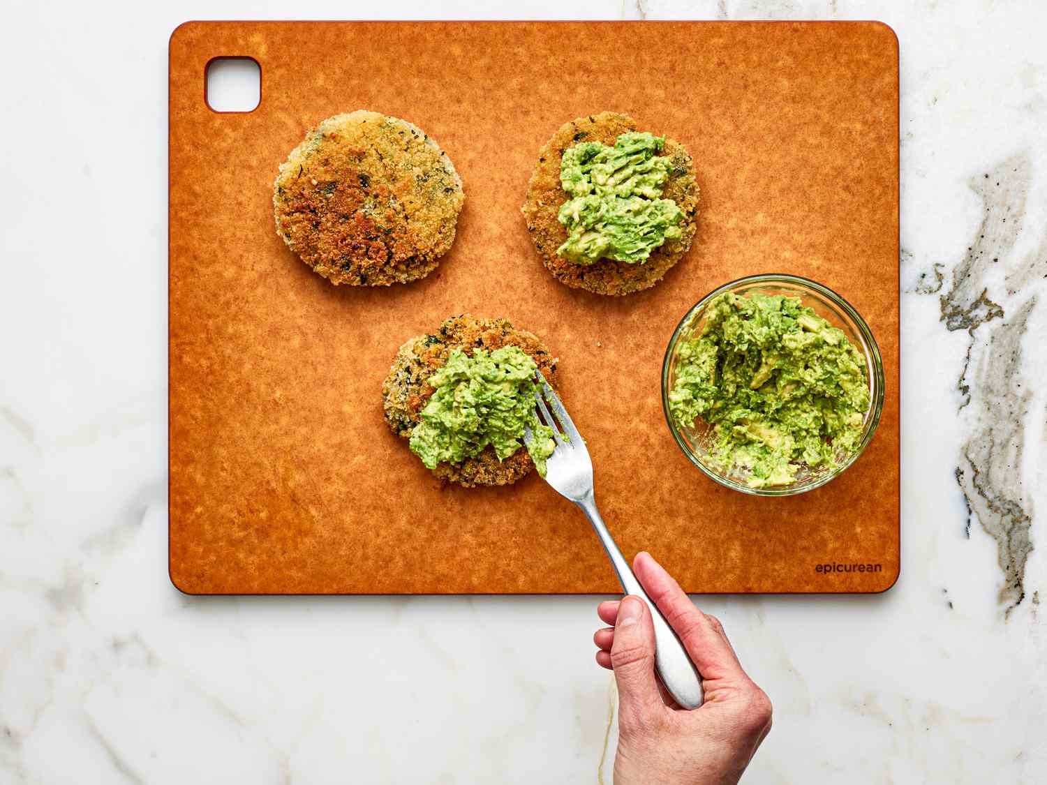 Overhead view of placing avocado on chickpea patties