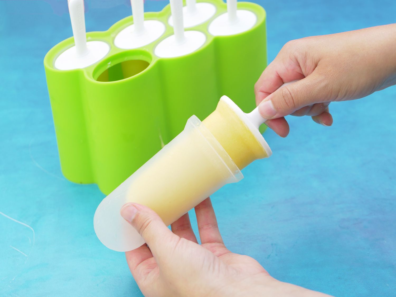 a hand pulling the popsicle out of the mold