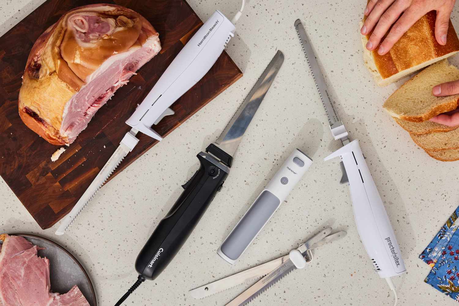 a variety of electric knives on a melamine countertop with ham and a piece of bread