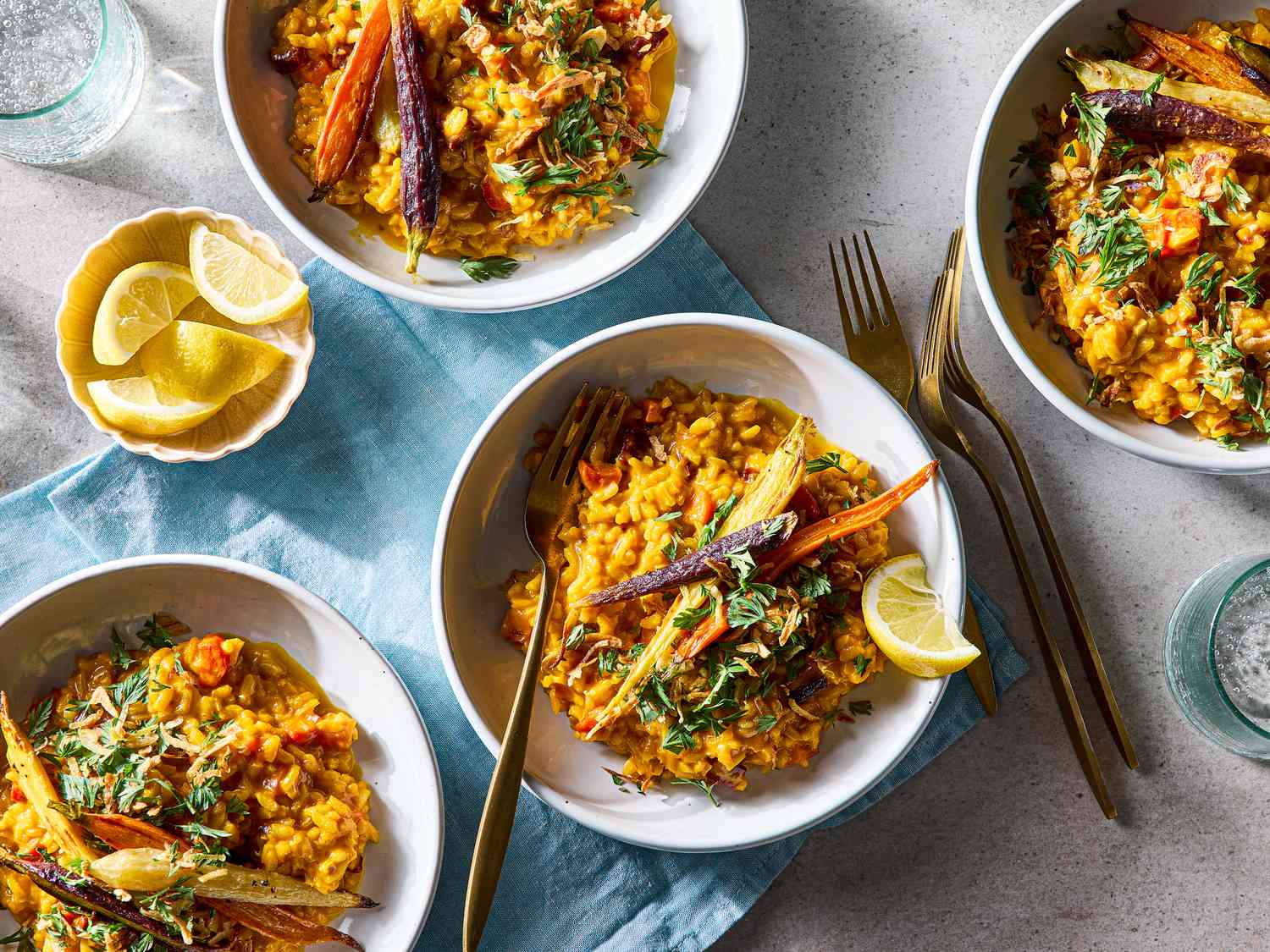 Plated carrot risotto with garnishes and lemon wedges