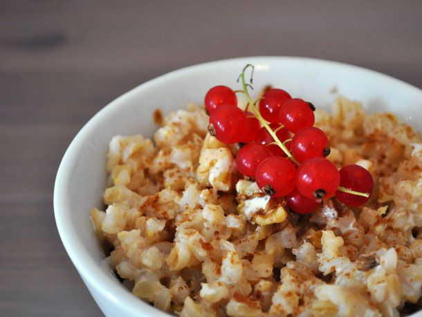 A bowl of barley porridge topped with red currants.