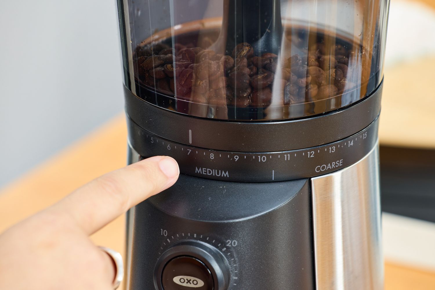 A person points to the different grind settings on the OXO Brew Conical Burr Coffee Grinder