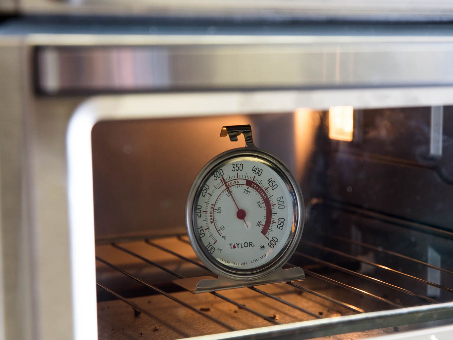 An oven thermometer on the rack of an oven.