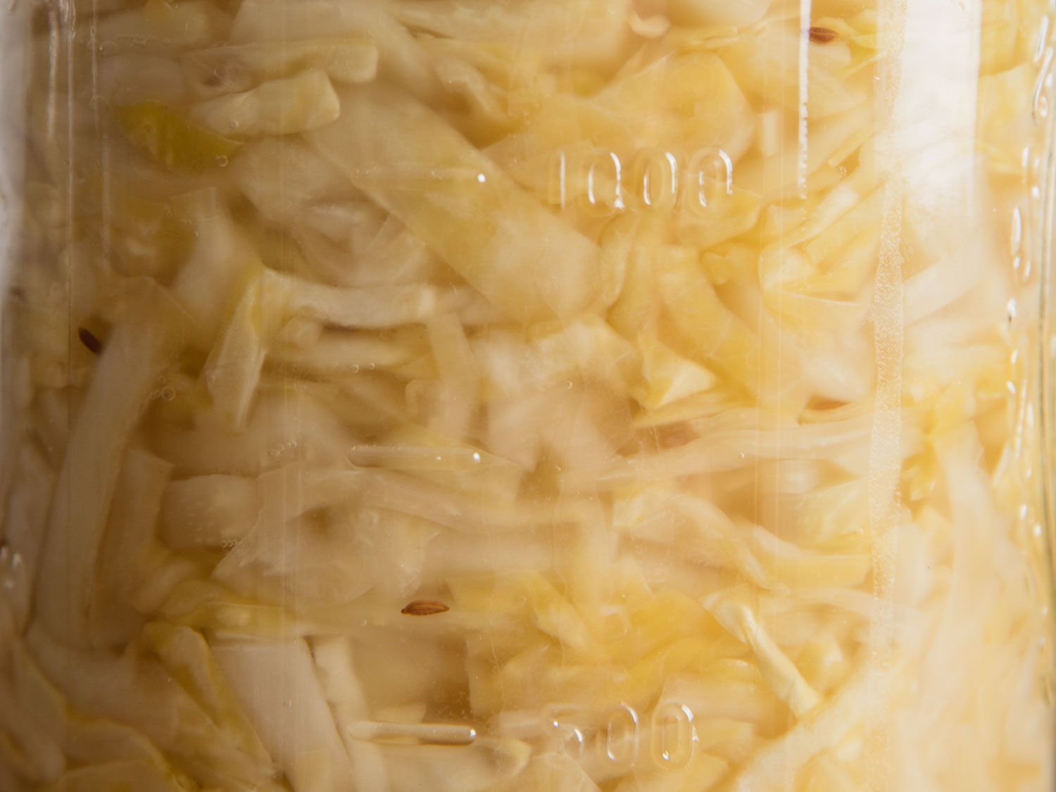 Closeup of homemade sauerkraut in a mason jar, submerged in its own brine.