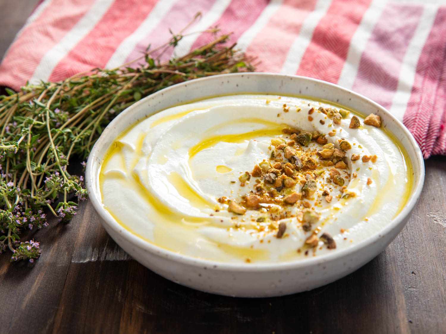 whipped feta in a white bowl and garnished with olive oil and crushed nuts