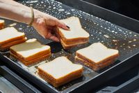 A person cooks grilled cheese sandwiches on the Weber Slate 30 Inch Griddle
