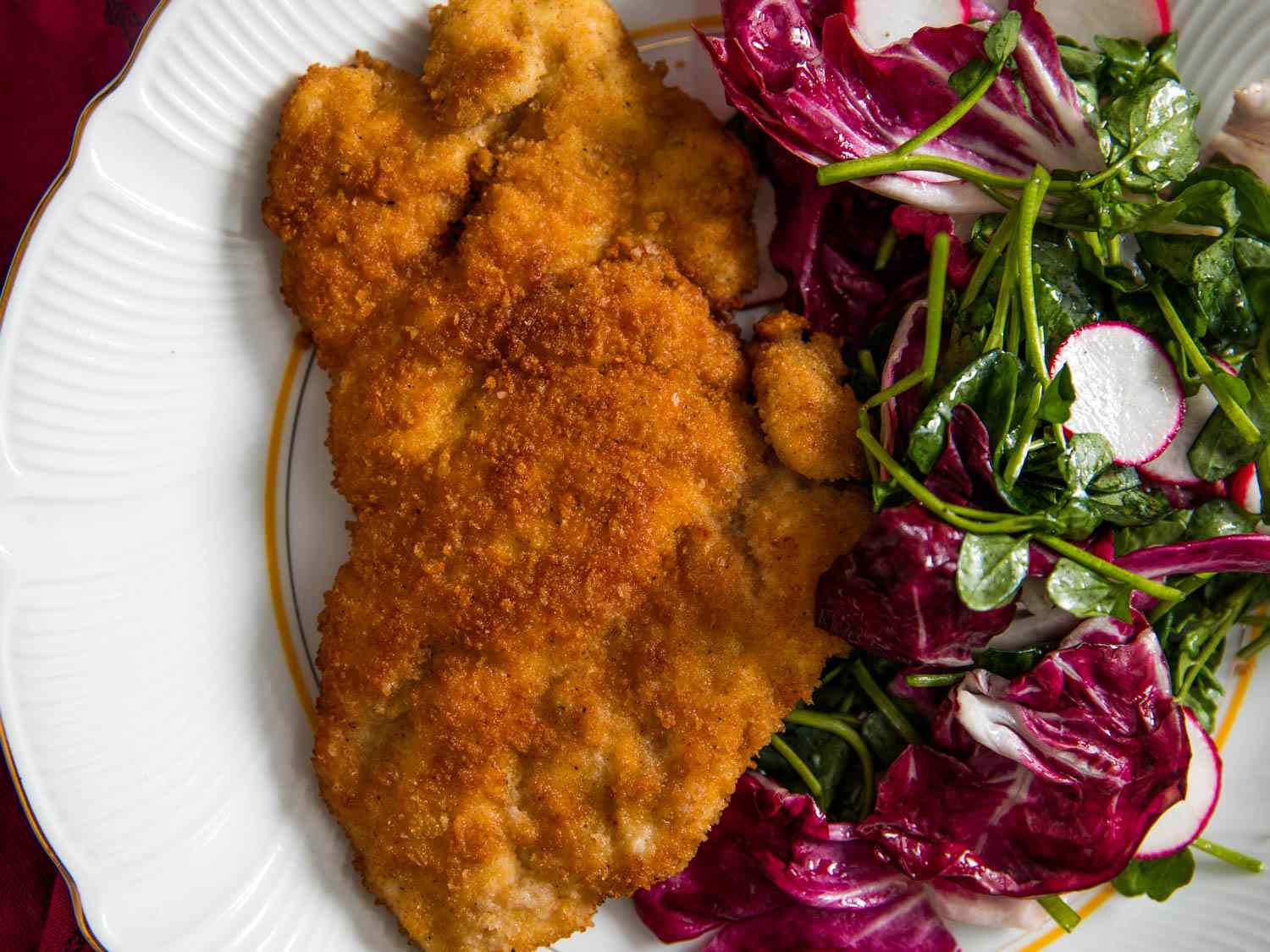 Close-up of a finished cutlet plated with a radicchio-watercress-radish salad.