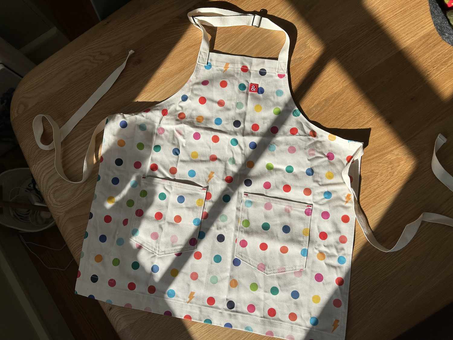 The Hedley & Bennett kids apron spread out on a wooden table in the sunlight.