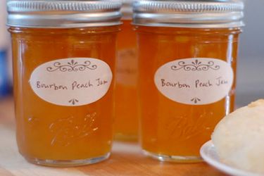 Profile view of two sealed half-pint jars of bourbon peach jam.