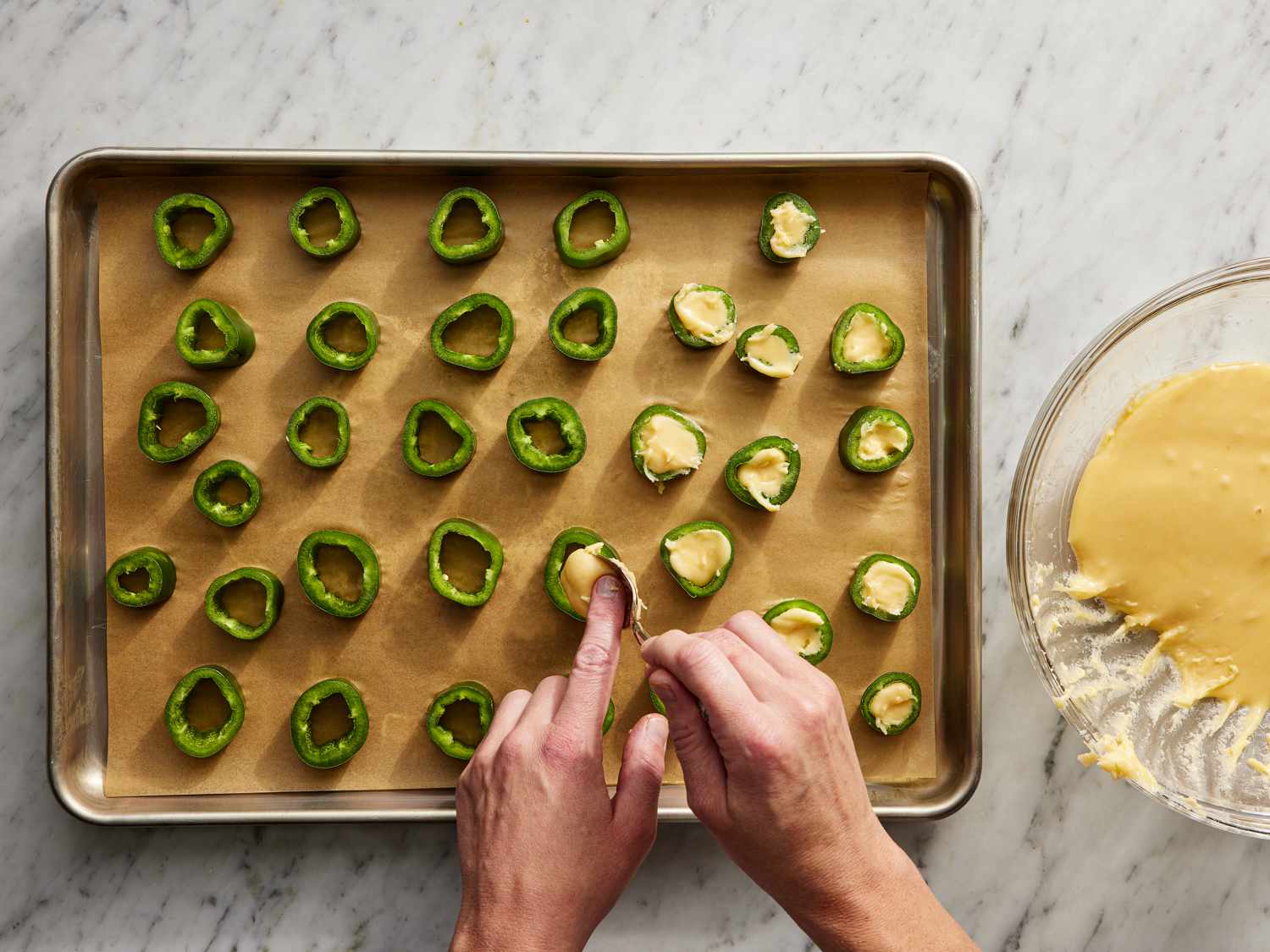 JalapeÃ±o rings being filled with sauce on a baking sheet