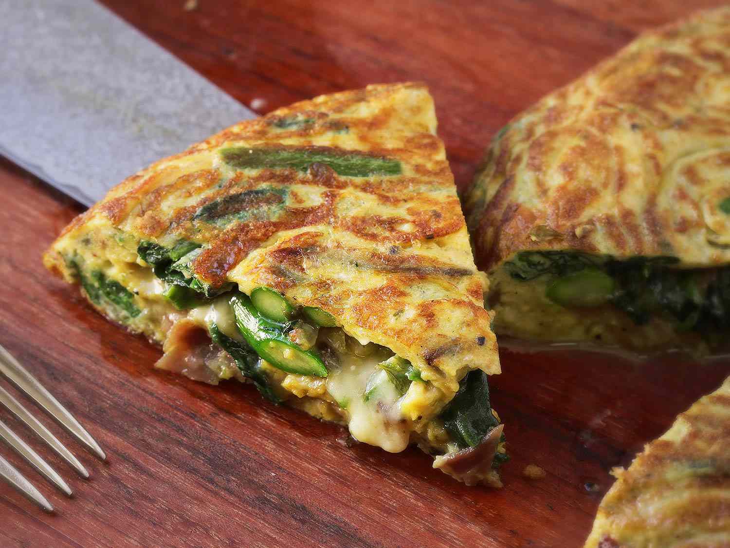 Closeup of an asparagus, spinach, ham, and cheese frittata.