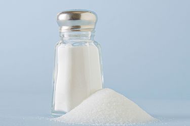 A salt shaker next to a small pile of salt