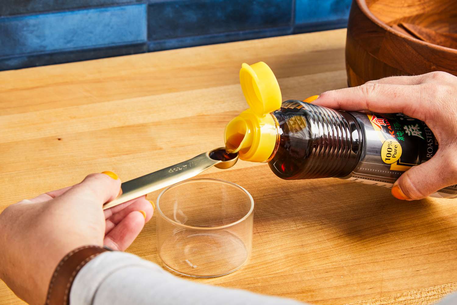 Soy sauce being poured from a bottle into a measuring spoon