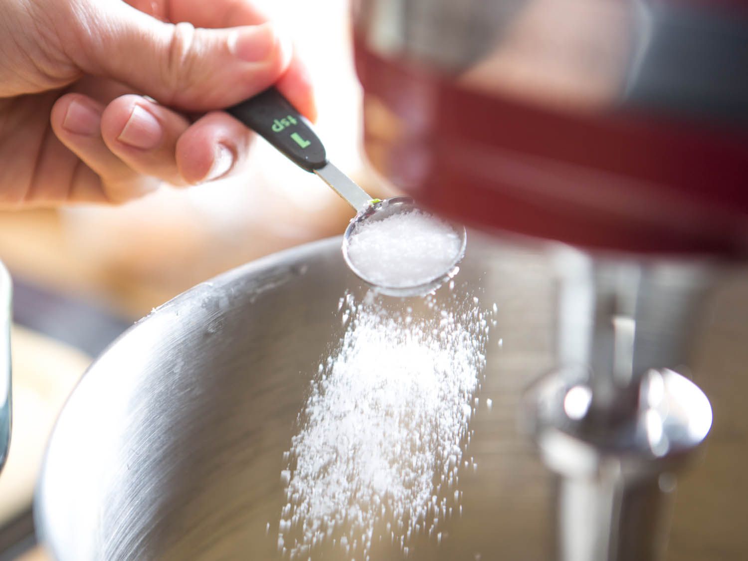 Adding salt to bowl of stand mixer for meatballs.