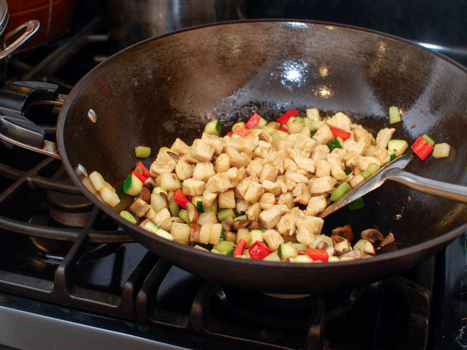 Stir-frying vegetables and chicken in a wok for cashew chicken ding.