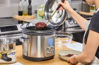 A person spoons beans from the Breville the Fast Slow Pro