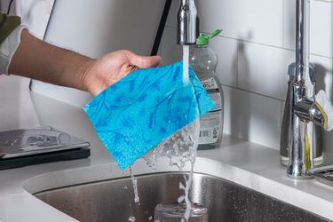 A Swedish dishcloth underneath a running faucet