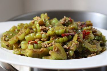 Stir fried bitter melon with ground pork and chiles on a platter. 