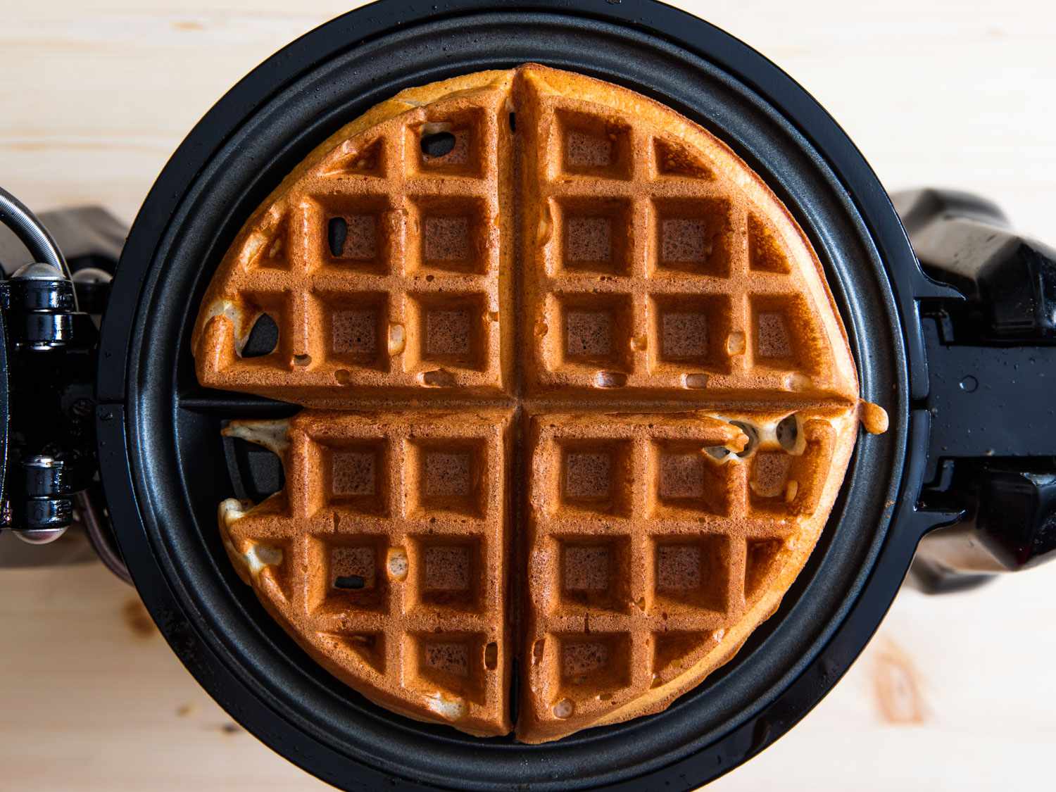 A finished waffle, looking brown and golden in a waffle iron. 