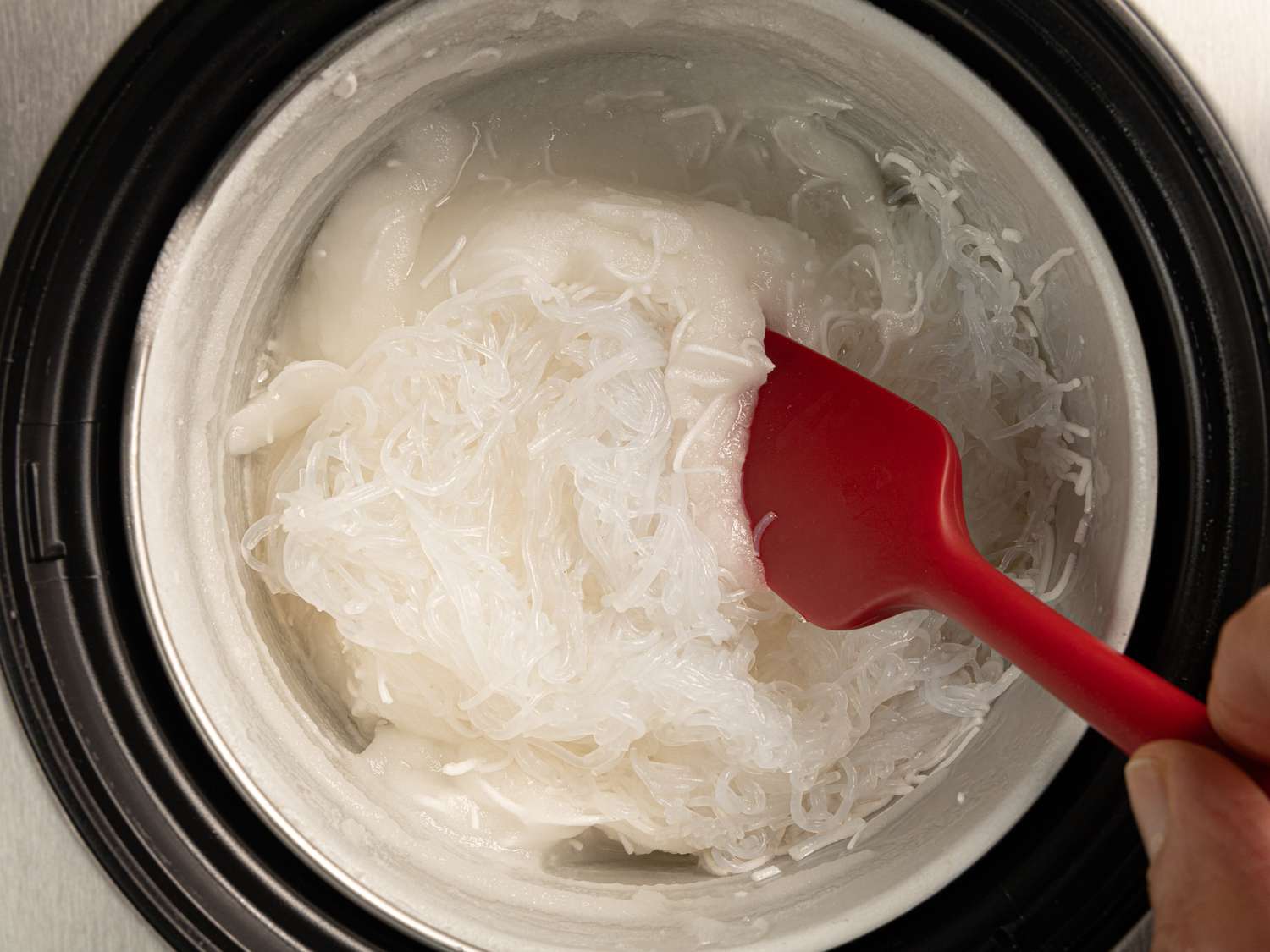Mixing noodles in with a silicone spatula