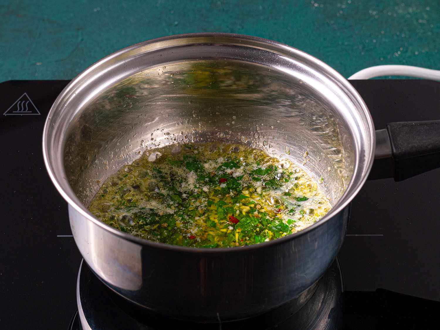 Butter and herbs inside of a stainless steel pot.