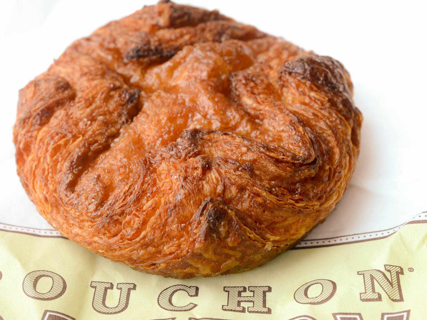 Kouign amann pastry on top of paper bag.
