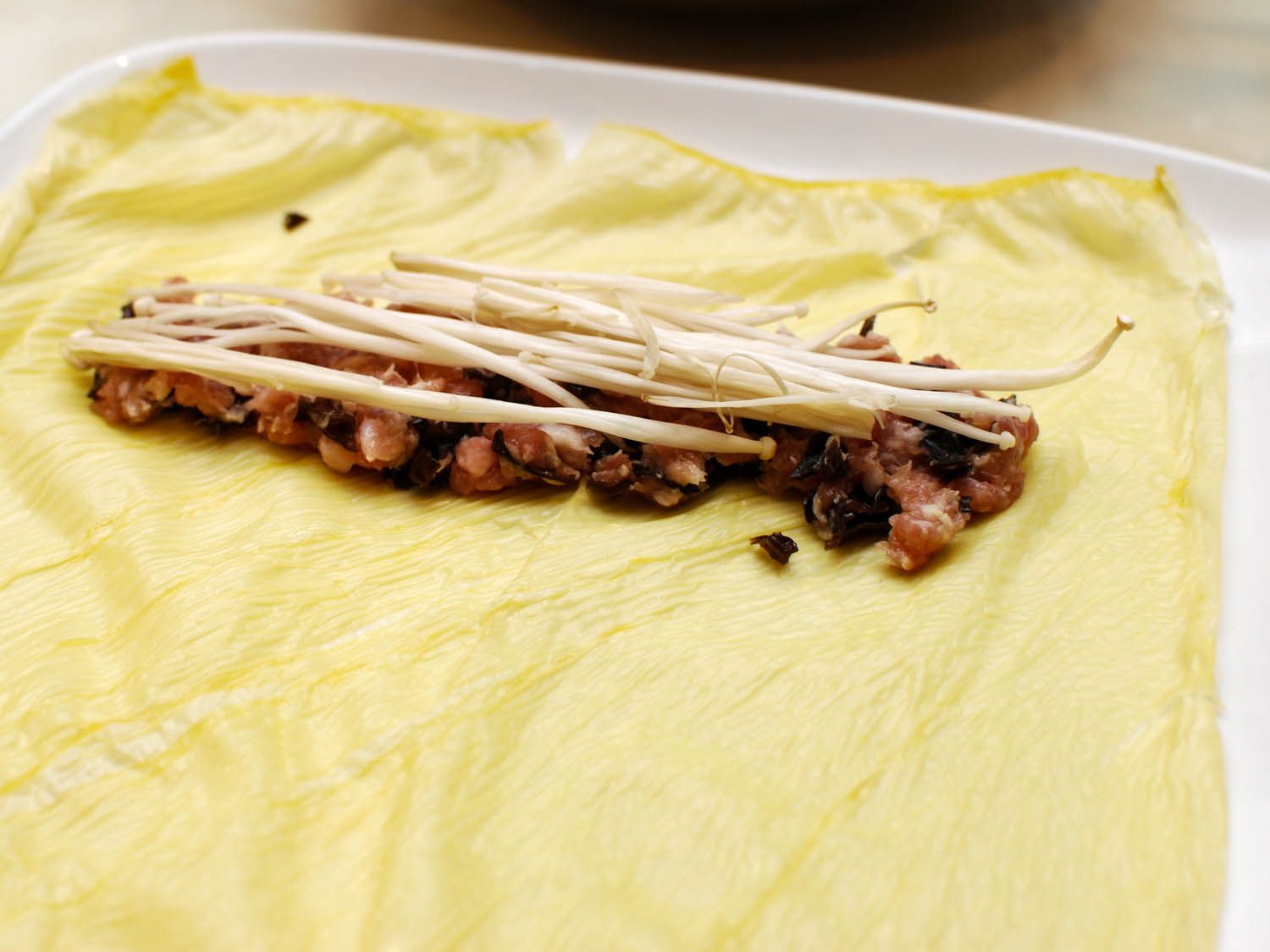 Half a dozen enoki mushrooms are laid on top of the pork filling.
