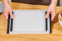 A person placing two OXO cutting boards down onto a countertop.