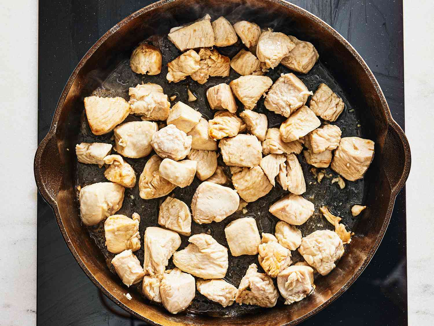Diced chicken cooking in a skillet 