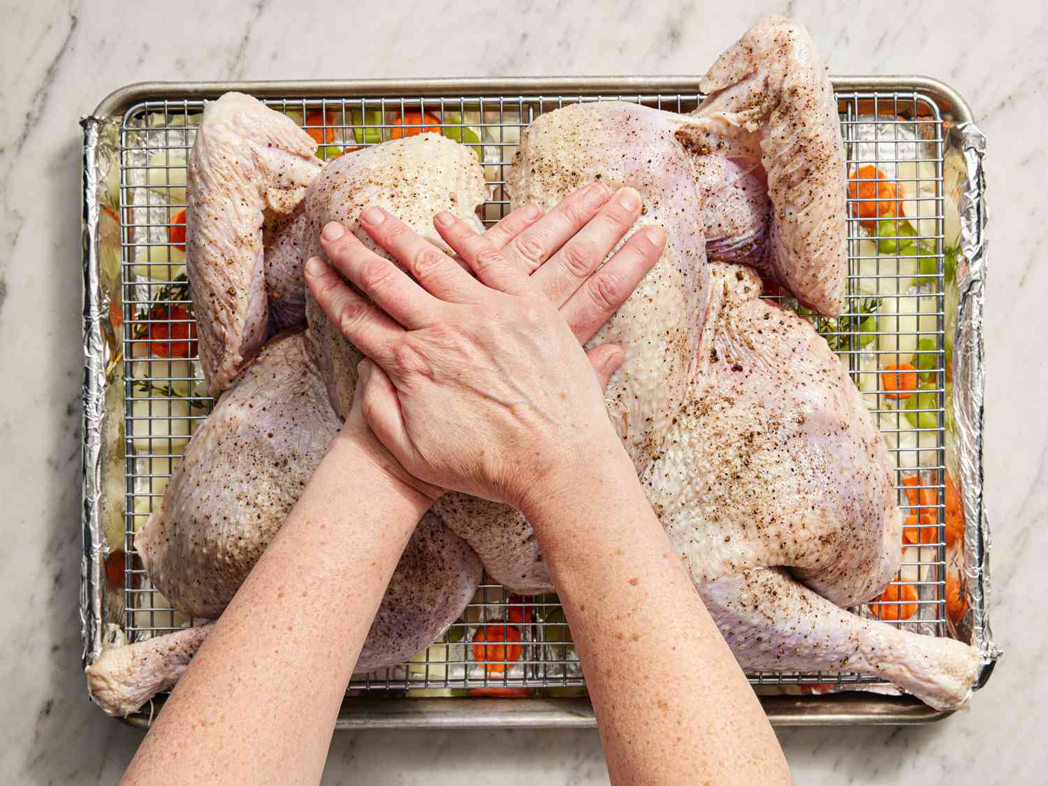 Two hands pressing down on the turkey breast to break it