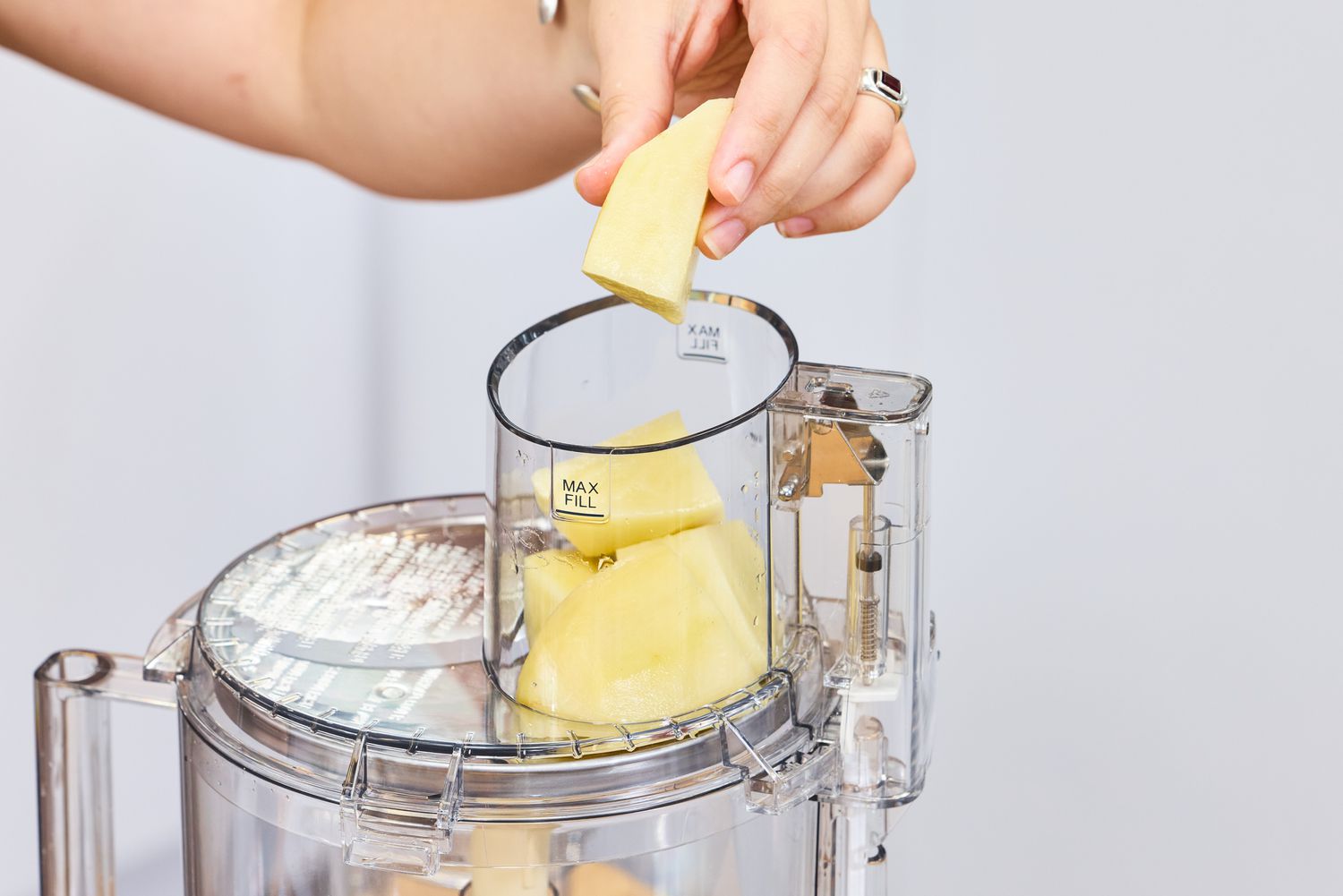 A person places parmesan cheese into the top of the Cuisinart 14-Cup Food Processor