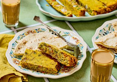 Dish of baked savory slices flatbread pickles and glasses of tea served on a table