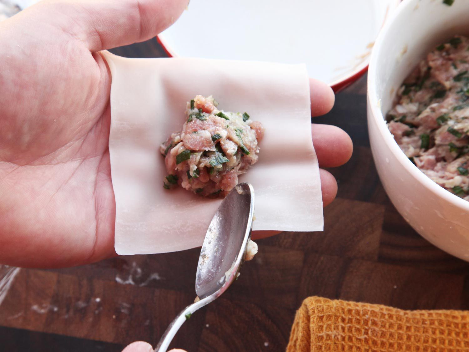 A tablespoon of wonton filling placed in center of wonton wrapper in hand